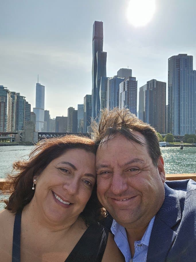 James Moss and his wife, Lori, in a selfie on the Chicago River with the city skyline behind.
